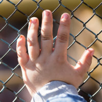 Child's hand on a grid of a metal fence Child's hand on a grid of a metal fence