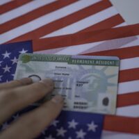 Permanent Resident Green card  of United states of America on flag of USA. Above close up view.