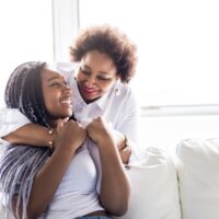 affectionate mother and daughter sitting on sofa