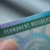 Close up view of Fragment of Permanent resident card (Green) card of USA on blurred background.