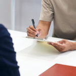 A black man and a Japanese female staff member signing documents