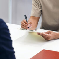 A black man and a Japanese female staff member signing documents A black man and a Japanese female staff member signing documents